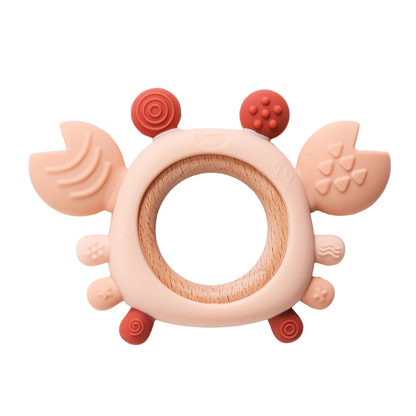 Close-up of a pink silicone crab baby teether with beech wood ring, designed for newborn gum relief
