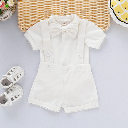 Toddler male model wears a baby boy gentleman romper, white top, navy shorts, suspenders, for photos