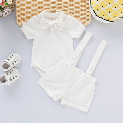 Close-up of a baby boy gentleman romper's plaid bow tie and navy suspenders detail, soft fabric