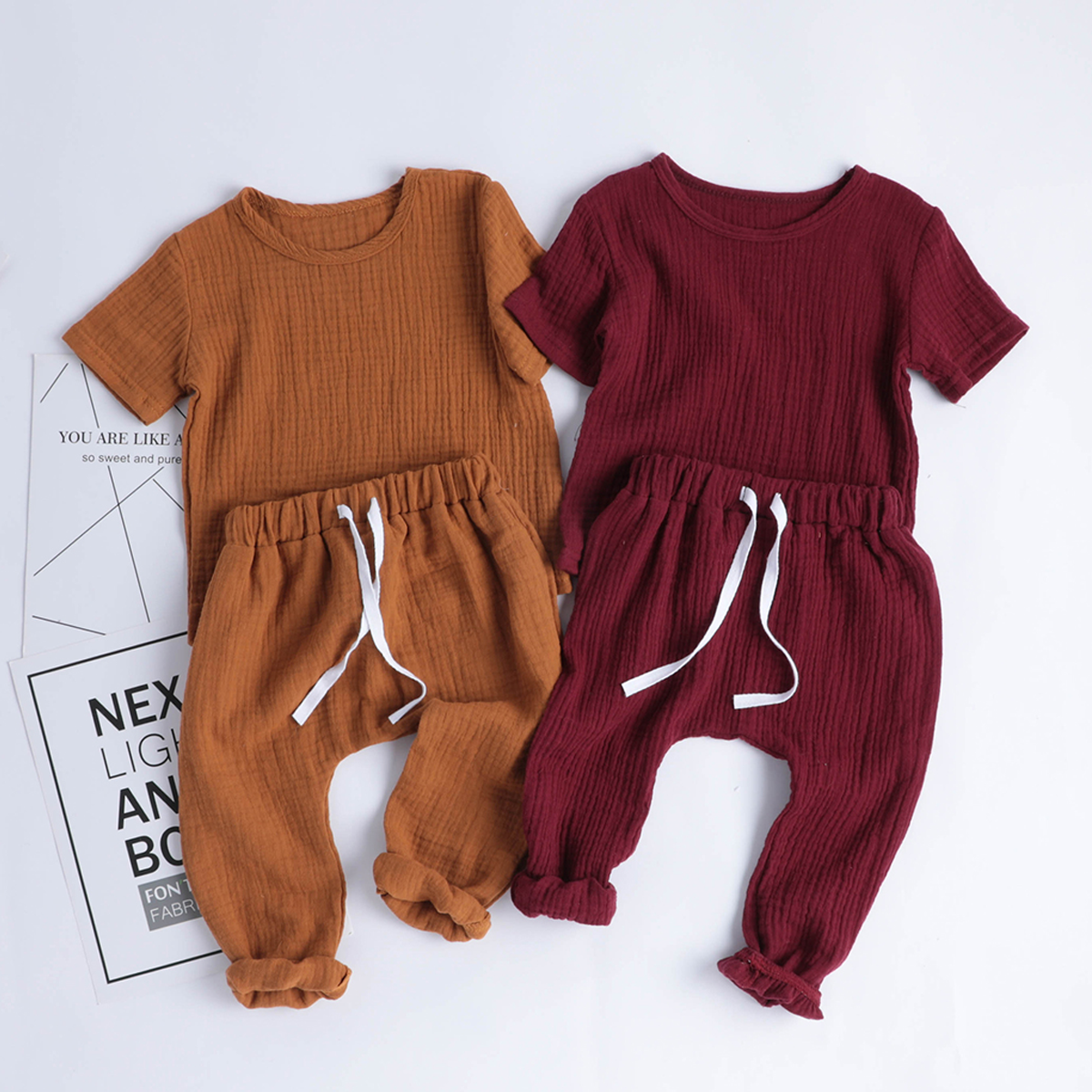 Stack of folded cotton baby bodysuits in various plaid patterns: red, yellow, and blue