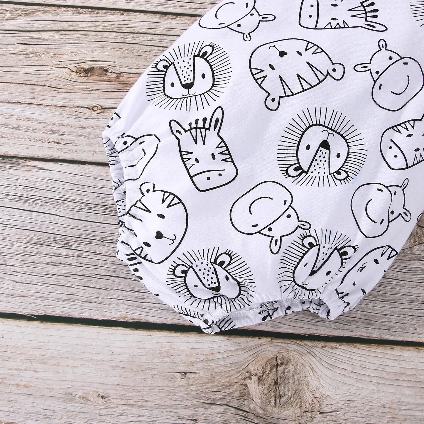 Close-up of the animal print on a baby boy sleeveless jumpsuit, showing fabric detail.