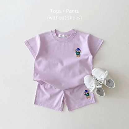 Casual toddler boy's outfit: pale blue t-shirt featuring a brown bear and plain white shorts