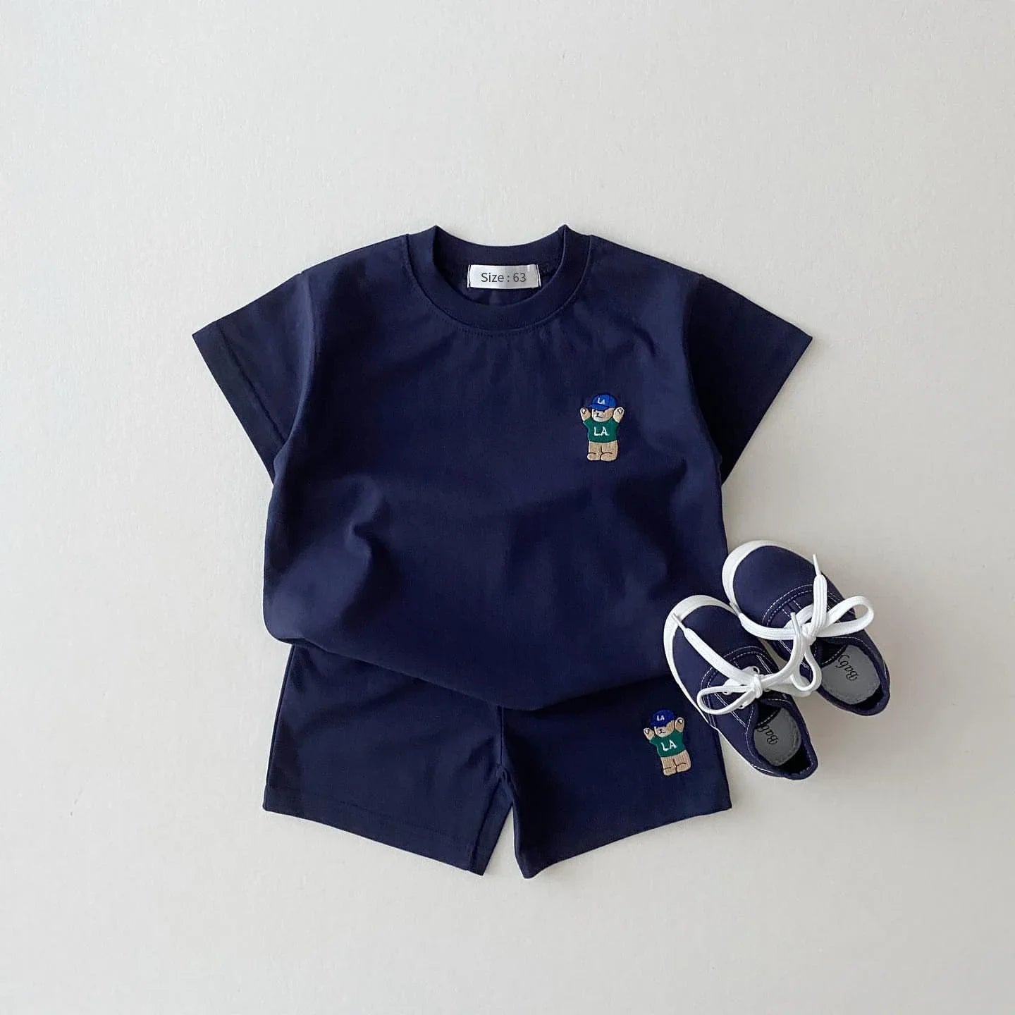 Two-piece infant apparel set featuring a light blue t-shirt with a sweet bear and simple white shorts