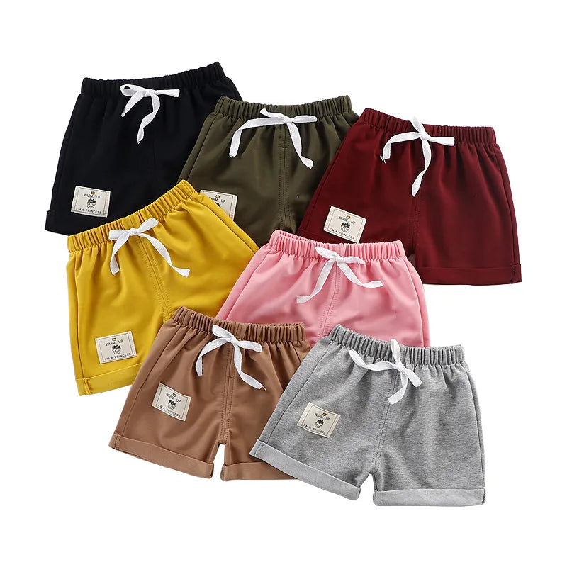 Baby boy wearing red solid polyester shorts with drawstring, perfect for summer casual wear.