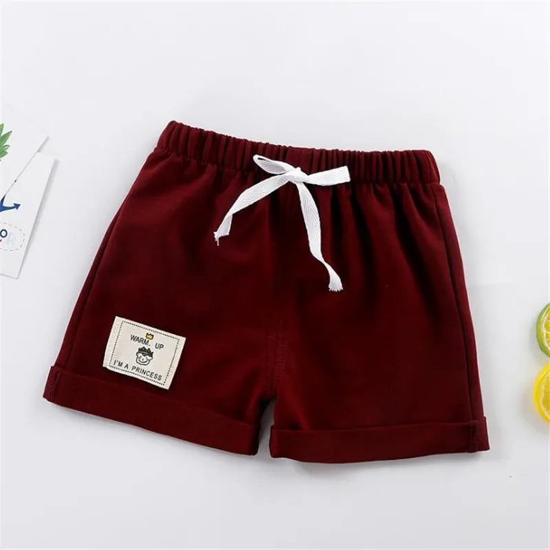 Close-up of green solid color boys' shorts, showing soft polyester fabric and drawstring waist.