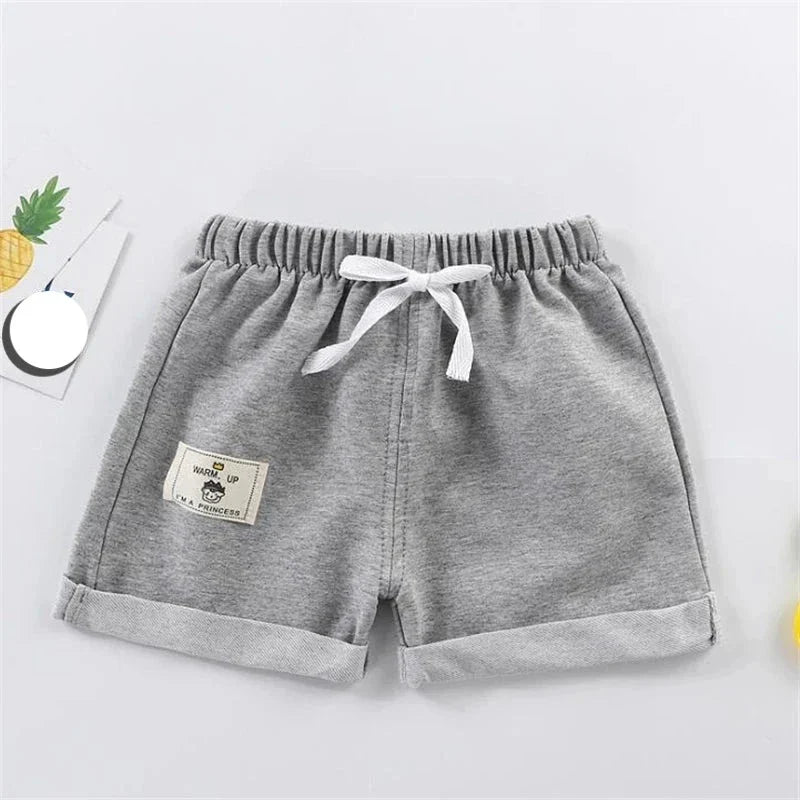 Little boy playing outdoors in comfortable gray polyester shorts, loose fit, perfect children's apparel.