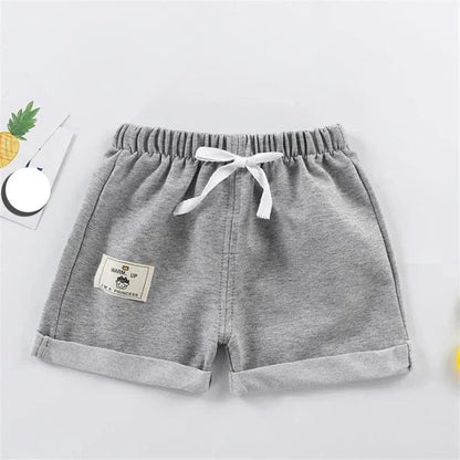 Little boy playing outdoors in comfortable gray polyester shorts, loose fit, perfect children's apparel.