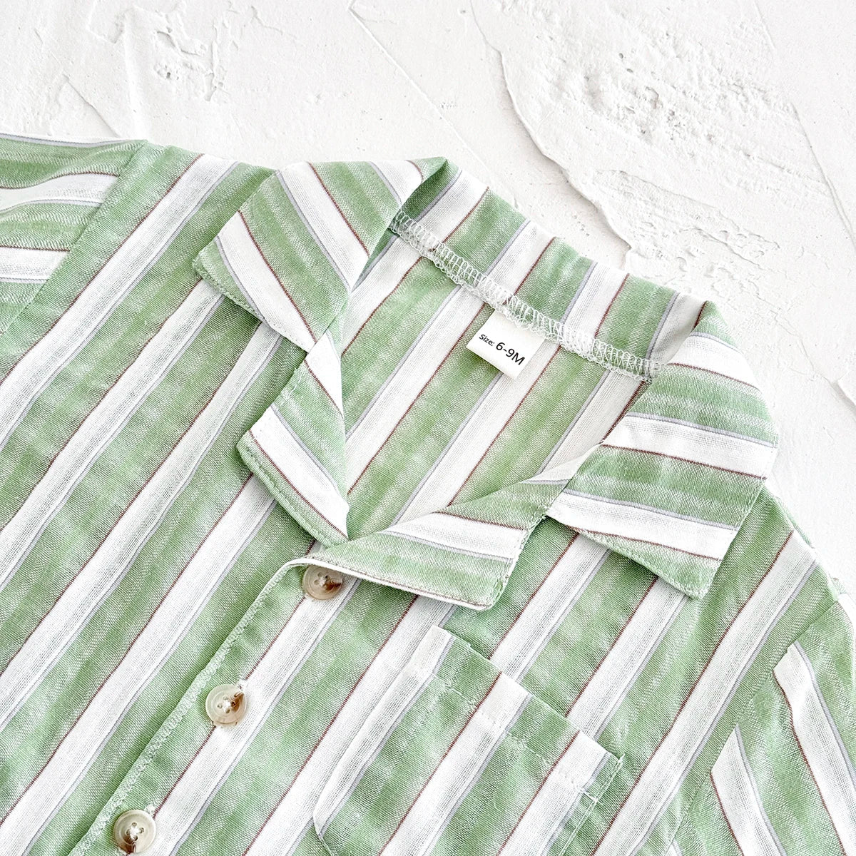 Unisex baby green stripe outfit on a mannequin, showcasing the summer style