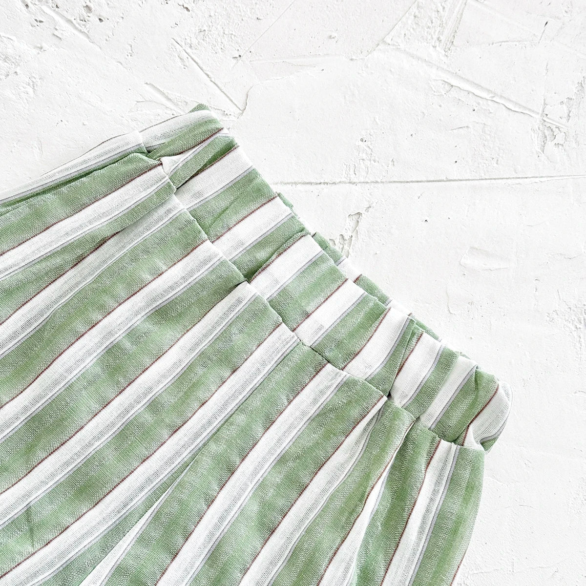 Close-up on the button detail of the green stripe lapel shirt in baby size