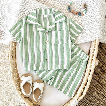 Toddler in a green stripe lapel shirt and matching shorts playing happily outdoors