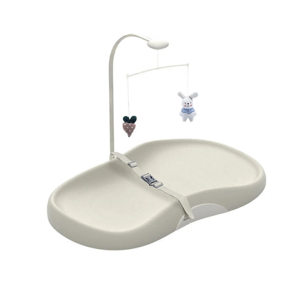 Nursery changing pad with contoured edges, safety strap, and engaging toy bar for happy baby care.