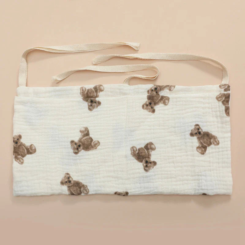 Open pockets of a cotton crib organizer, showing space for various baby care products.