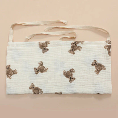 Open pockets of a cotton crib organizer, showing space for various baby care products.