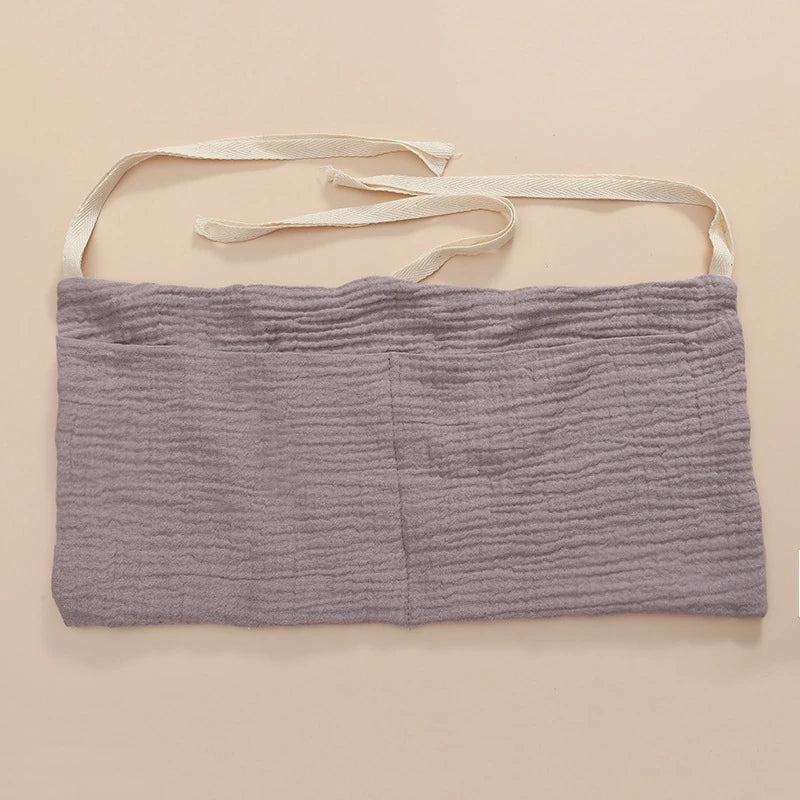 Hanging cotton organizer on a white crib, displaying practical storage for baby accessories.