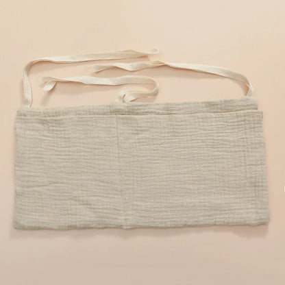 Full view of a baby crib with an attached cotton storage bag, keeping baby items within reach.
