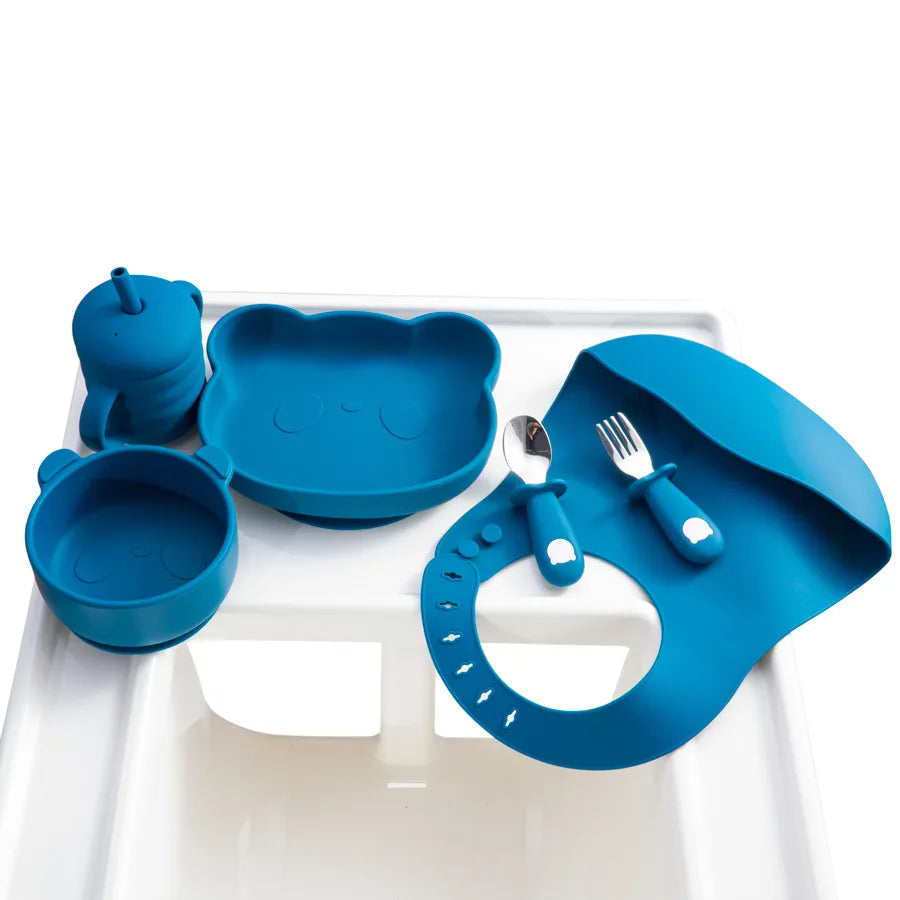 Parent helping baby with a silicone spoon and fork set, encouraging independent feeding