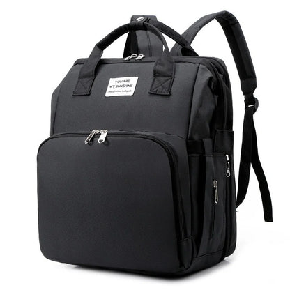 Diaper bag backpack that converts to a baby crib, with a USB interface and changing pad.