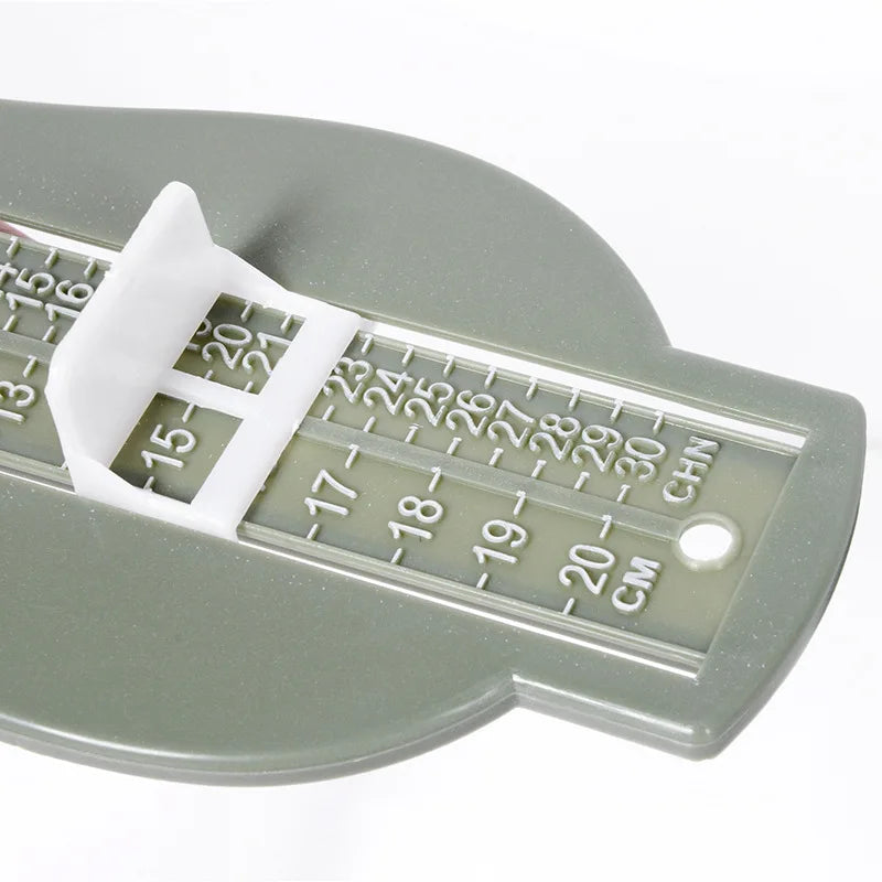 Kids footwear helper: Baby foot gauge tool on a wooden surface with baby shoes