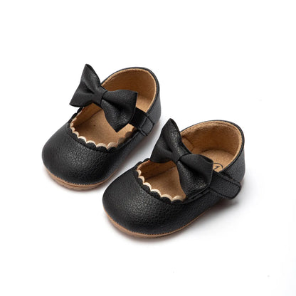 Side view of a baby girl's first walker shoe, anti-slip soft sole and decorative bow