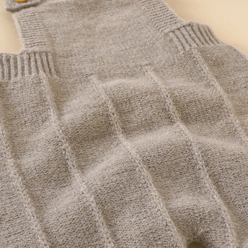 Newborn baby girl smiling while wearing a comfortable knitted sleeveless romper and hat