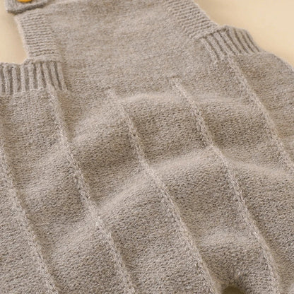 Newborn baby girl smiling while wearing a comfortable knitted sleeveless romper and hat