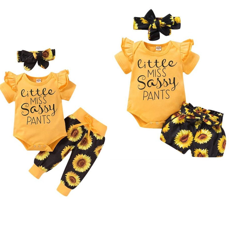 Baby girl in a vibrant yellow sunflower romper and matching bow headband set, perfect for summer.