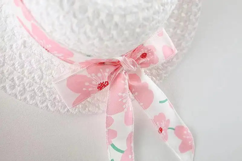 Hanging display of the white floral bow summer dress, ready for a baby girl to wear and enjoy.