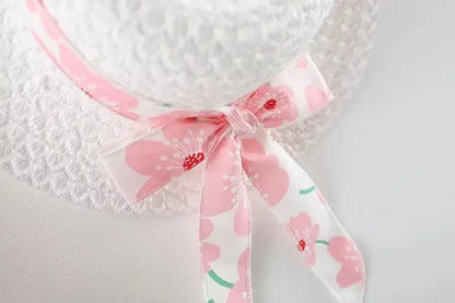 Hanging display of the white floral bow summer dress, ready for a baby girl to wear and enjoy.