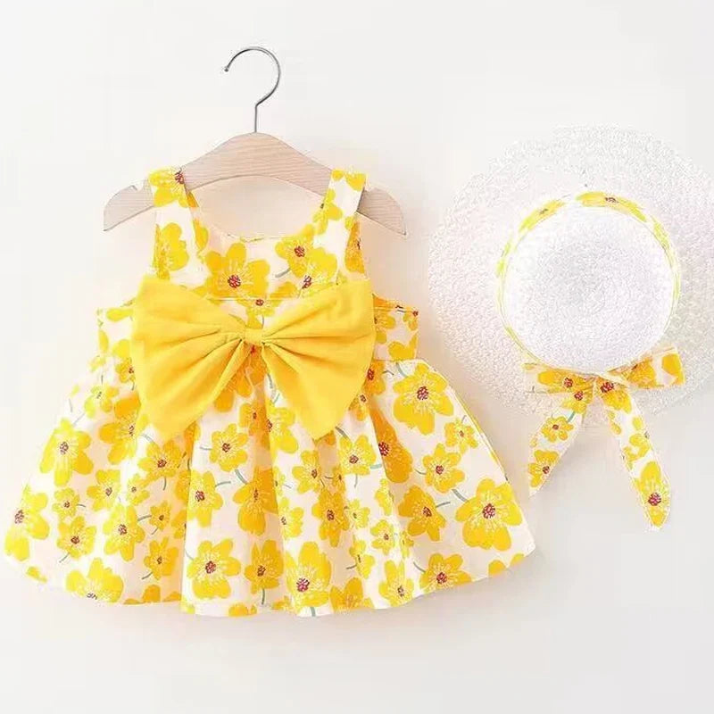 Full shot of a cute baby girl wearing a white floral knee-length summer dress with a bow.