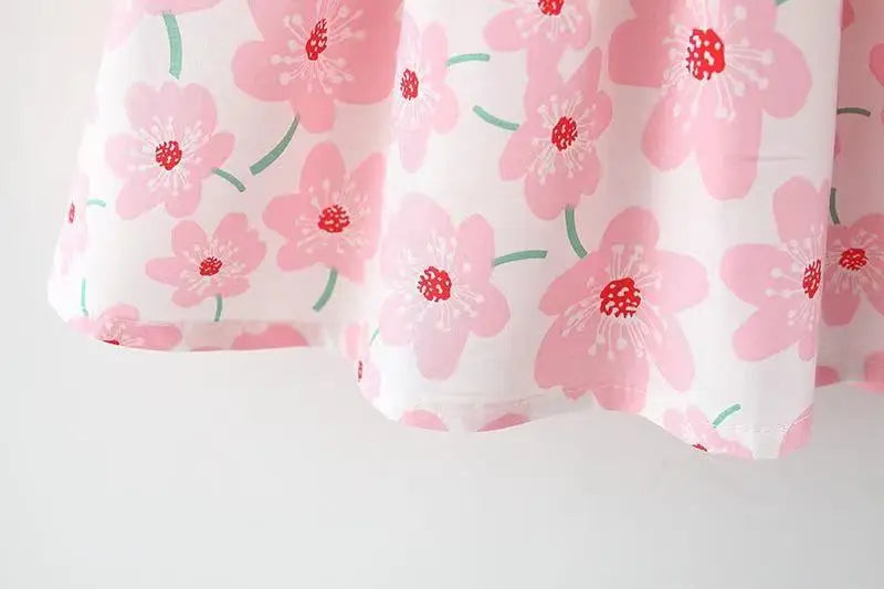 Detail of the bow on a white floral summer dress, an essential part of this baby girl's outfit.