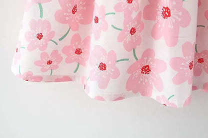 Detail of the bow on a white floral summer dress, an essential part of this baby girl's outfit.