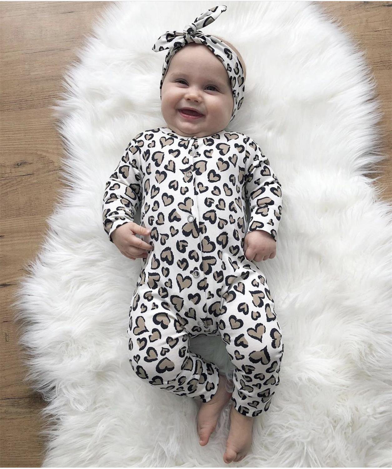 Newborn girl wearing an adorable cotton heart print jumpsuit and coordinated headband.