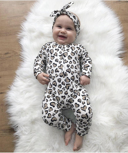Newborn girl wearing an adorable cotton heart print jumpsuit and coordinated headband.