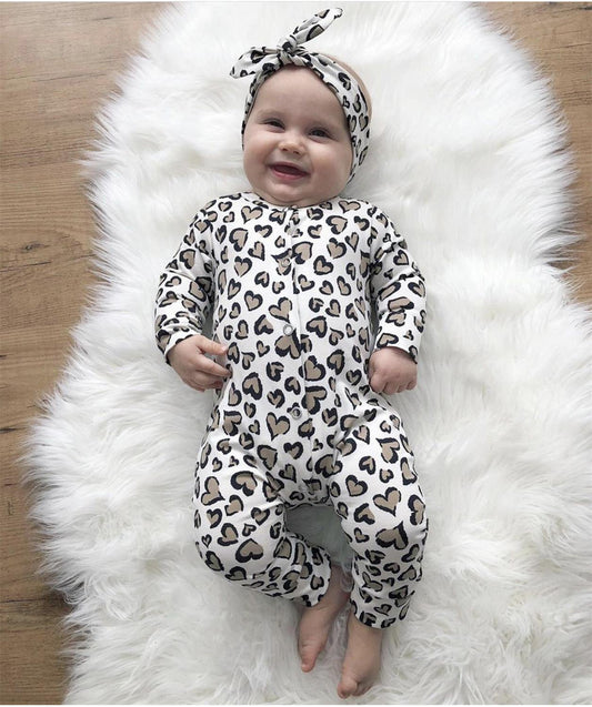 Newborn girl wearing an adorable cotton heart print jumpsuit and coordinated headband.