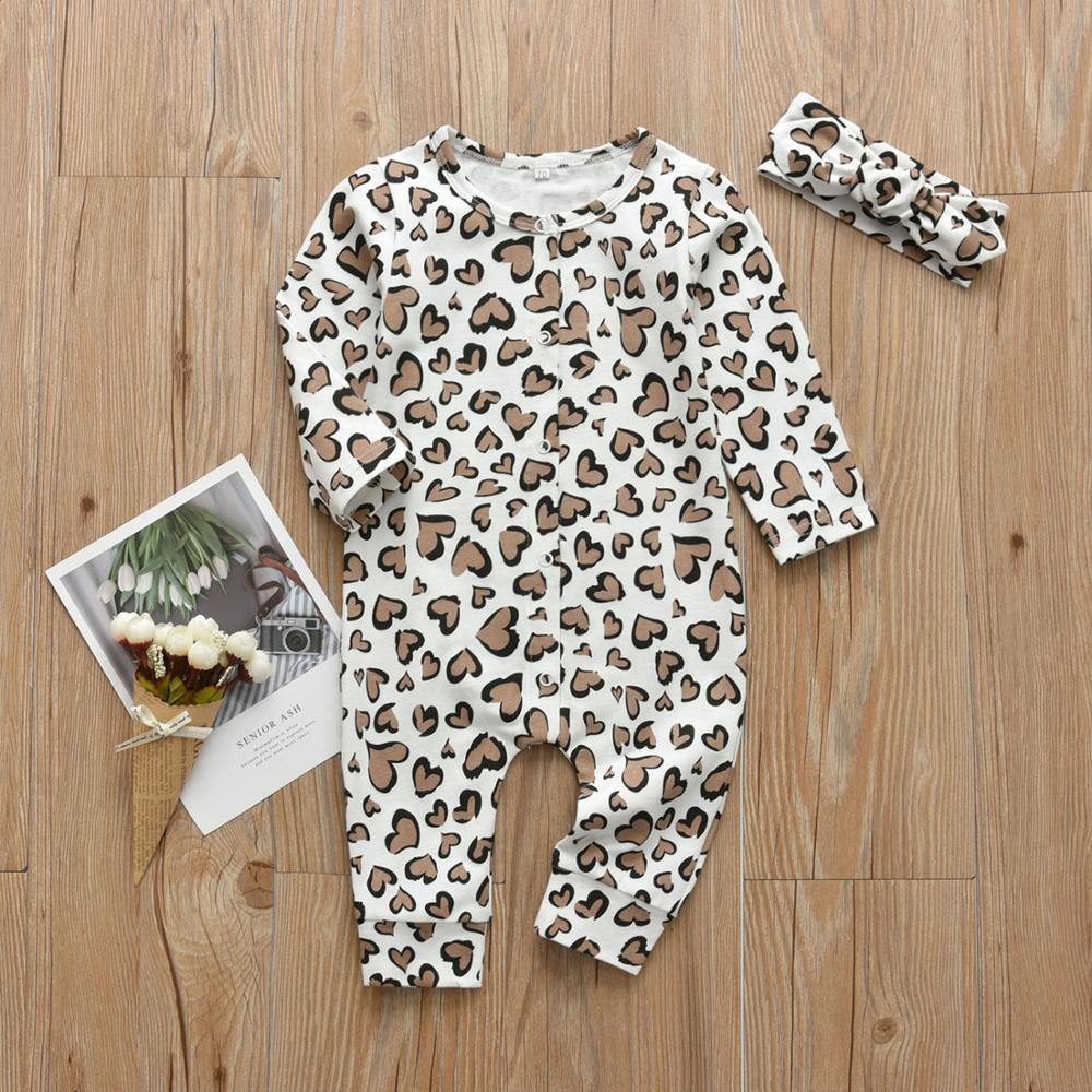 Close-up of heart print cotton jumpsuit fabric for baby girls with a soft headband.