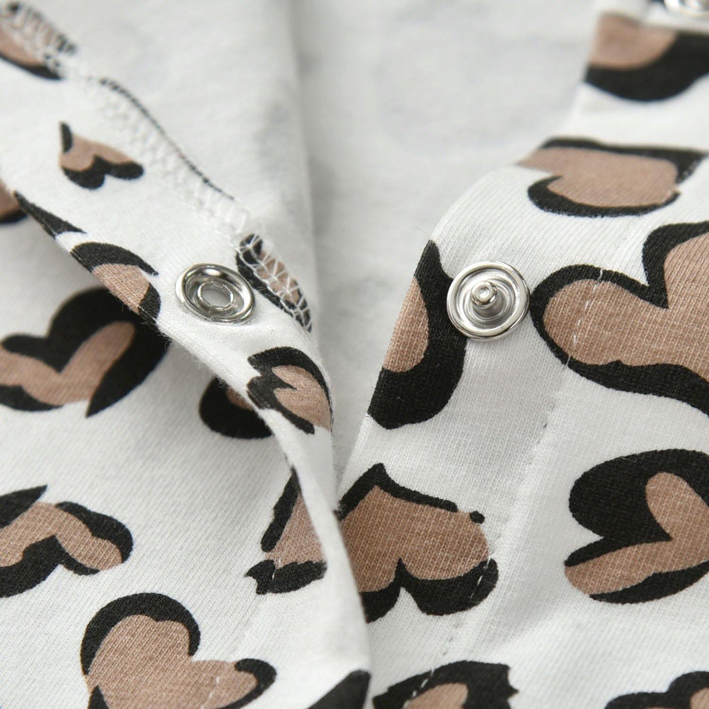Full view of a baby girl jumpsuit with heart print design and an included headband.
