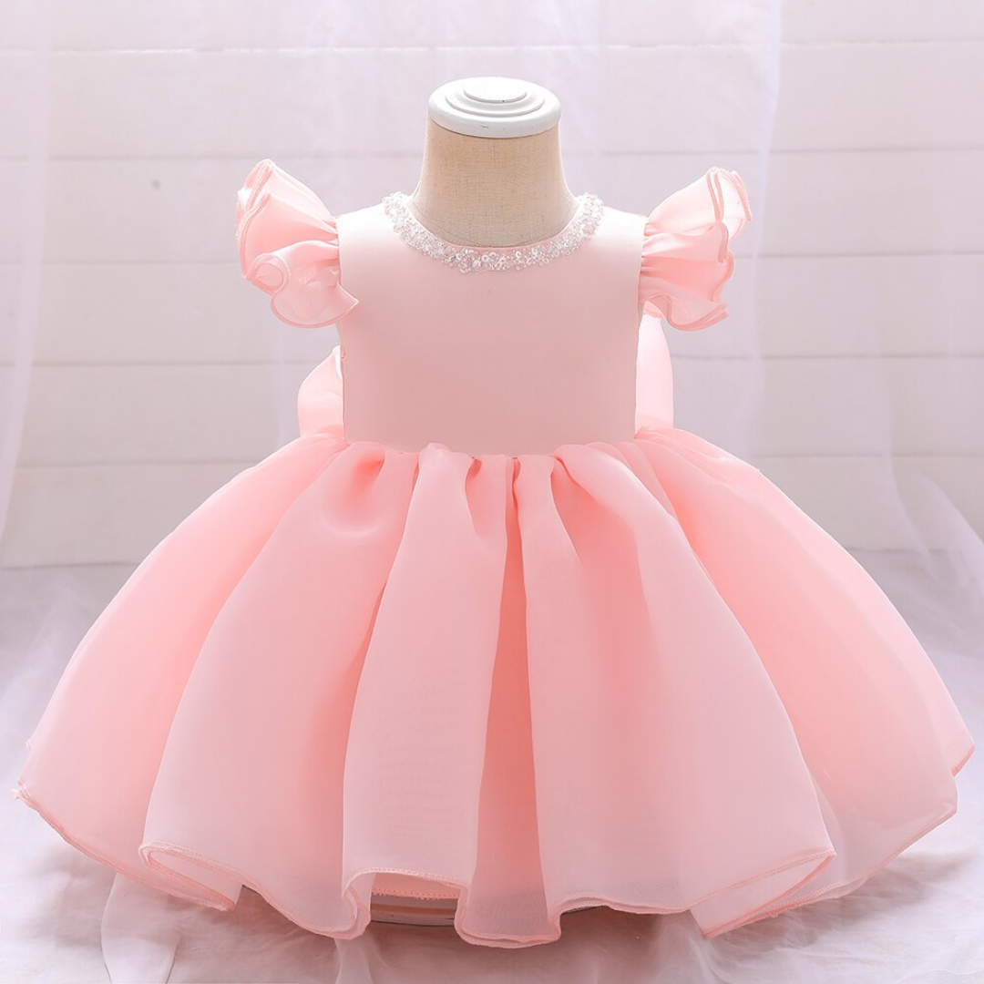 Baby girl in elegant pink beaded bow princess ball gown, perfect for special occasions, close-up.