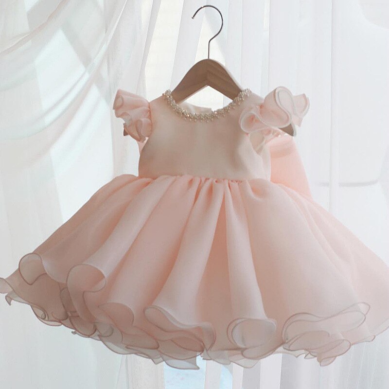 Back view of a baby girl's elegant princess ball gown featuring a prominent, oversized bow.