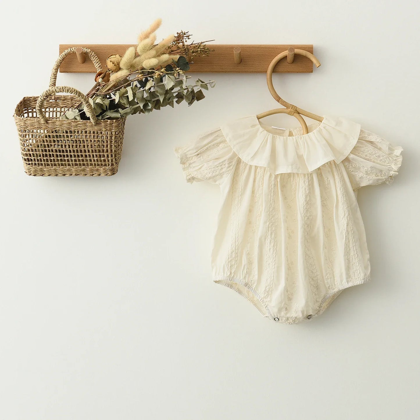 Front view of a white lace baby girl romper with long sleeves, suitable for baby's first photos.