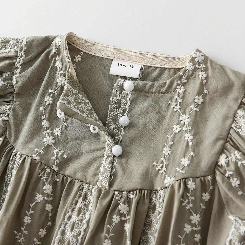 Close-up of the lace fabric and button details on a charming long sleeve baby girl jumpsuit.