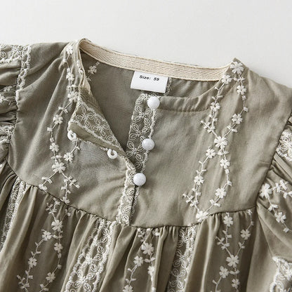 Close-up of the lace fabric and button details on a charming long sleeve baby girl jumpsuit.