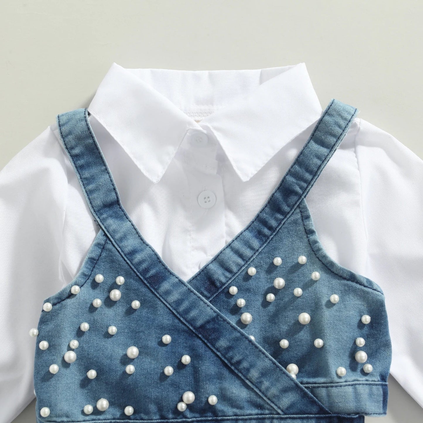 Close-up of beaded denim vest on a baby girl's long sleeve dress outfit, stylish kids fashion.