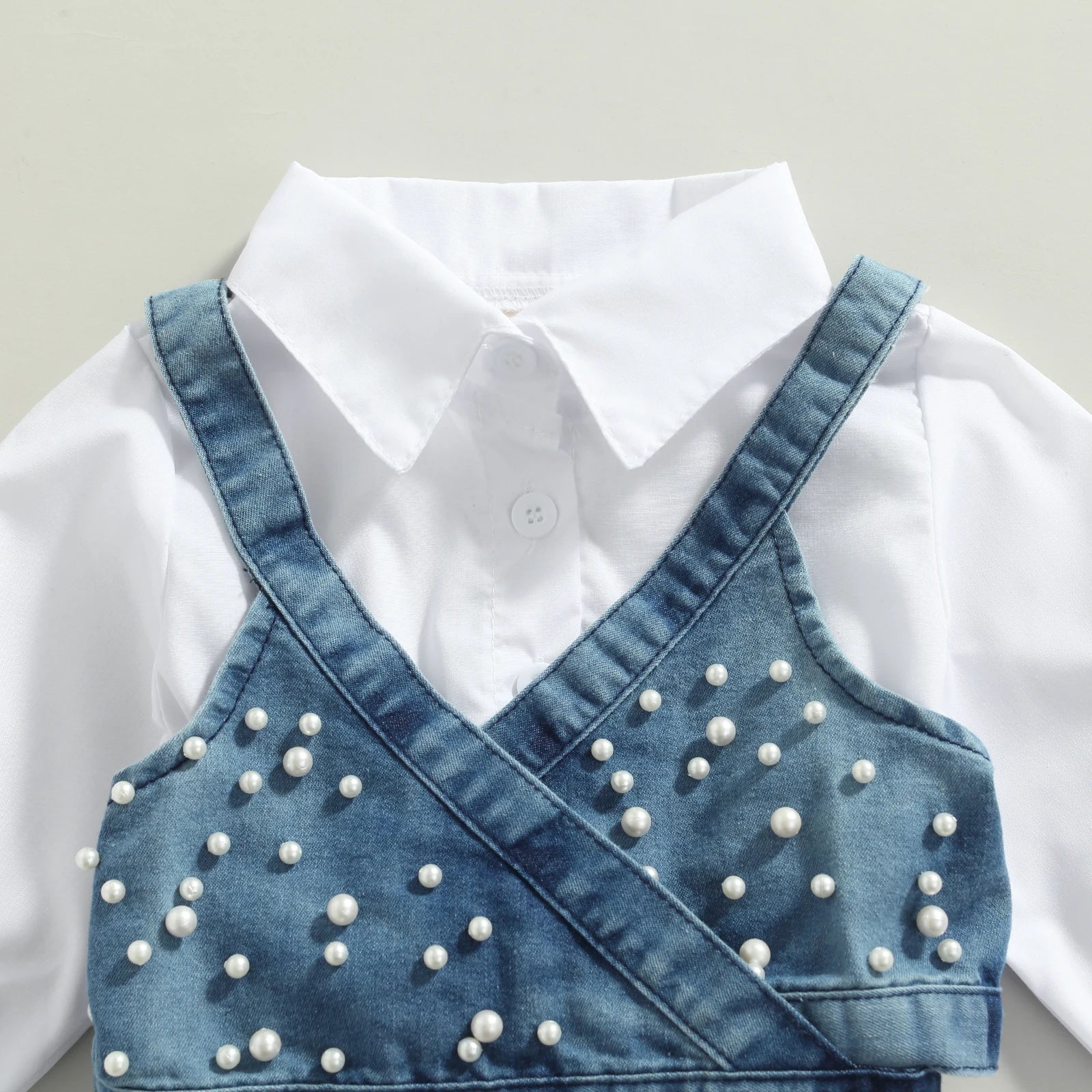 Close-up of beaded denim vest on a baby girl's long sleeve dress outfit, stylish kids fashion.