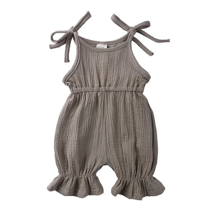 Side view of a baby girl wearing a striped cotton sleeveless romper jumpsuit.