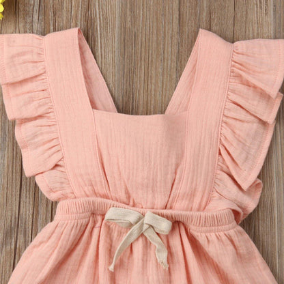 Close-up of pink frilly ruffle romper for baby girl, delicate fabric, bowknot detail