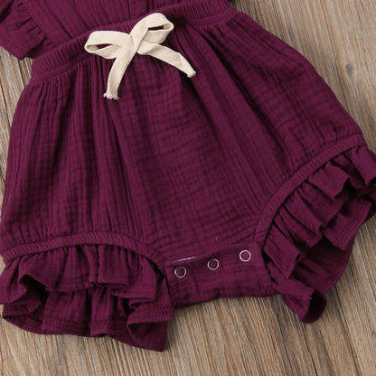 Toddler girl smiling in vintage-style cotton blend ruffle romper with bow