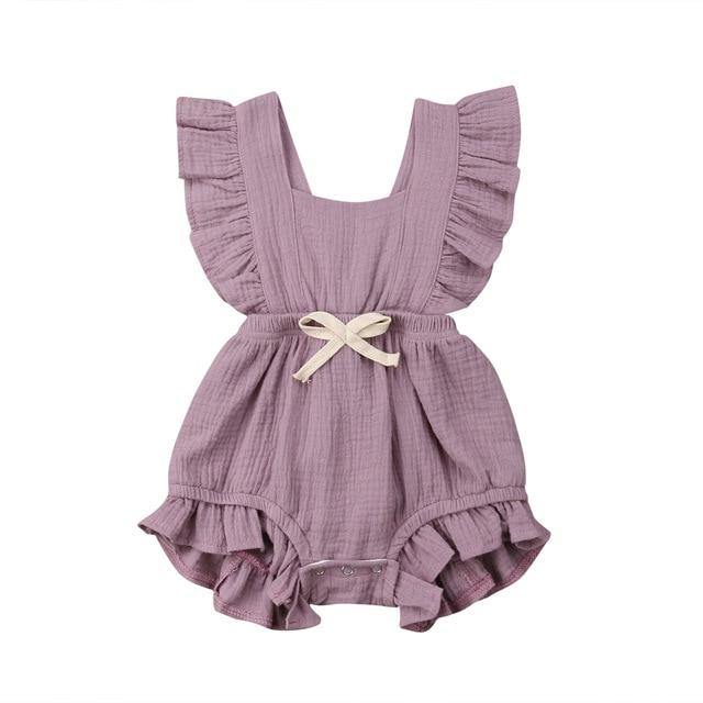 Close-up of the bowknot detail on a frilly baby girl's pink cotton blend romper