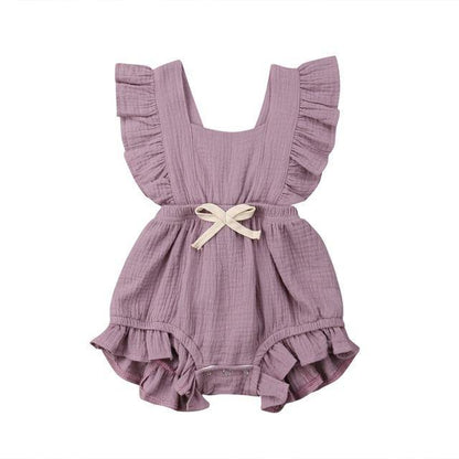 Close-up of the bowknot detail on a frilly baby girl's pink cotton blend romper