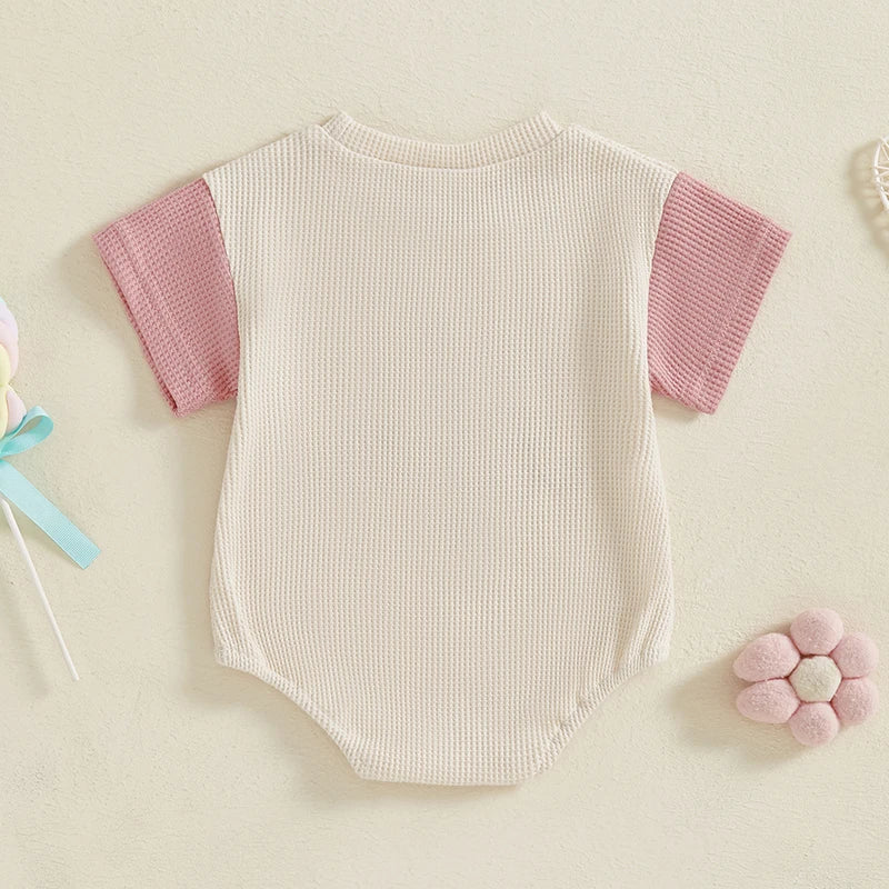 Close-up of waffle knit fabric on a baby girl's summer romper with detailed embroidery.