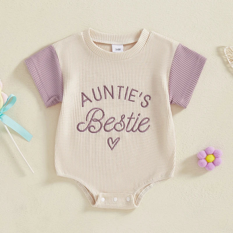 Infant girl sitted in a pink embroidered waffle knit romper, perfect short sleeve jumpsuit for summer.